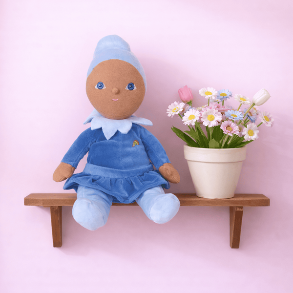 Doll in a blue outfit with a flower pot on a pink background