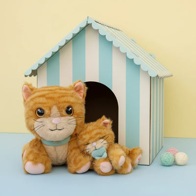 Dinkum Pets ginger cat plush toys sit outside a pastel striped playhouse with soft brushable fur and playful details beside three knitted balls