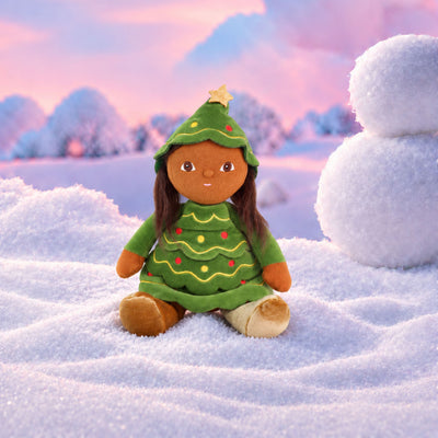 Plush doll with long dark brown hair and embroidered brown eyes, dressed as a Christmas tree in a green tiered, scalloped dress with gold wavy stitching and red and yellow bauble dots, a matching hood topped with a gold star, and gold velvet boots.