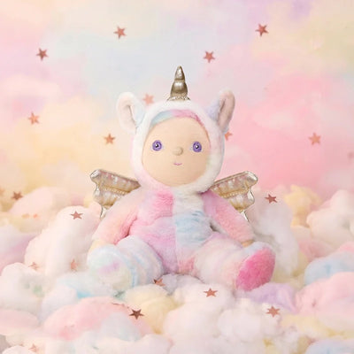Dinky Dinkums pastel unicorn plush doll with soft rainbow fur golden wings and a silver horn sitting among fluffy clouds beneath a starry pink sky
