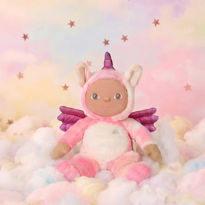 Pink unicorn plush doll with purple wings and a tiny rainbow on its belly sitting among pastel clouds against a dreamy starry backdrop from Dinky Dinkums