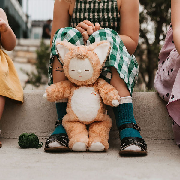 Little girl plays with her ginger tabby cat, soft plush toy dinkum doll for kids