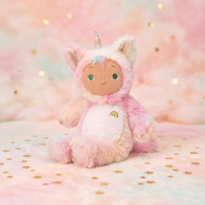 Pink plush kittycorn toy with cat ears and silver horn in a fluffy pink outfit with rainbow detail seated on a pastel star patterned blanket