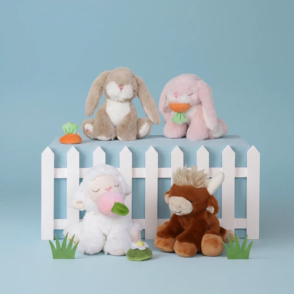 Four plush toys on a small white picket fence against a light blue background