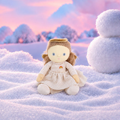 Plush doll dressed as an angel, with fluffy light-brown hair in pigtails, embroidered blue eyes, a gold velvet halo and wings, a cream velvet top with a small rainbow patch, a cream tulle skirt with gold glitter dots, and cream booties.