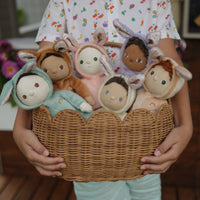 Six Dinky Dinkums bunny dolls with soft floppy ears nestled in a wicker basket held by a child for imaginative play