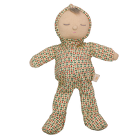 Soft baby doll with sleepy embroidered closed eyes, a smiling mouth and a tuft of brown hair, wearing a cream footed sleepsuit and matching bonnet printed with small red and green sprigs.