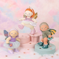 Three fairy figurines on colorful stands with a pastel background