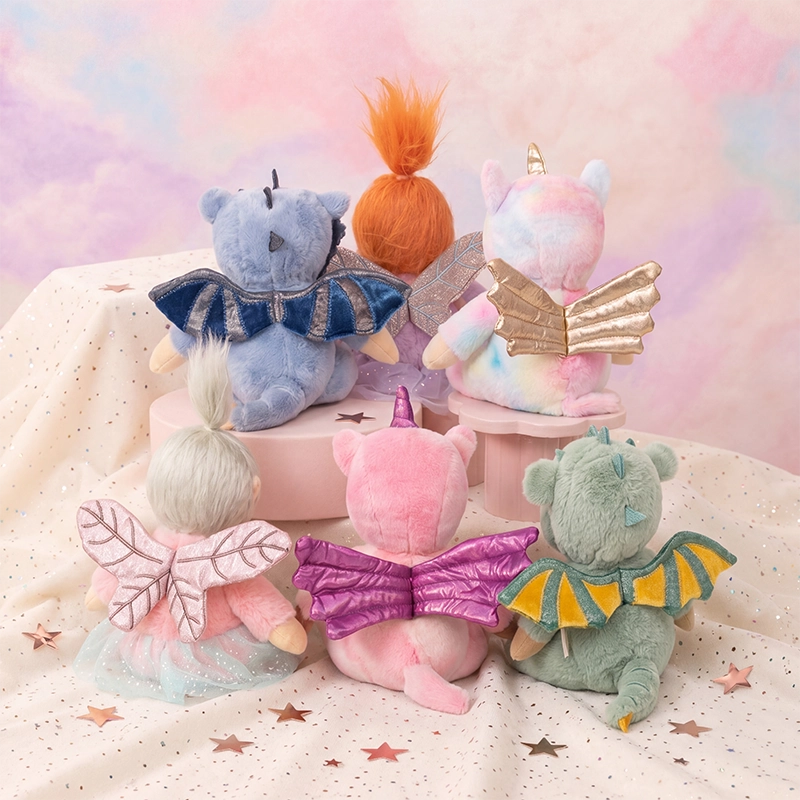 Five Dinky Dinkums plush dolls in pastel fantasy costumes gathered on a starry blanket including a pink unicorn with golden wings and colorful fairy friends