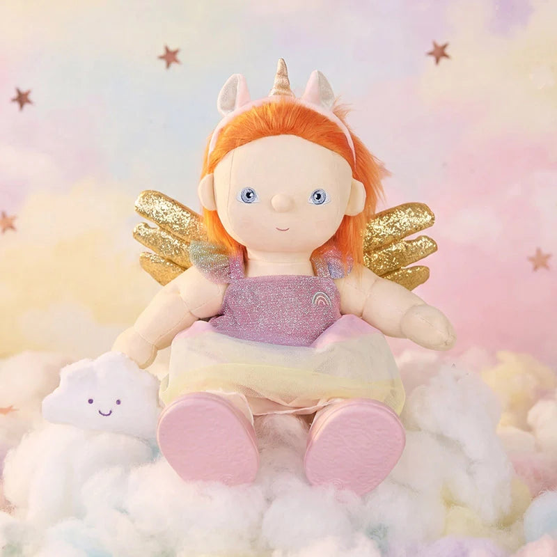 Dinkum Dolls Unicorn Nova doll with bright ginger hair unicorn horn gold wings and pink outfit sitting on soft clouds beside a smiling cloud friend