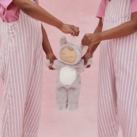 Dozy Dinkums Cozy Dinkums lavender unicorn plush toy held by children wearing pink striped overalls against a soft pink background