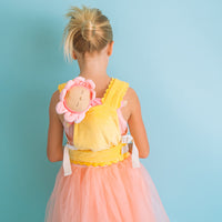 Child wearing a yellow Petal Carrier with a pink flower faced doll on her back shown from behind Dinkum Dolls accessory for imaginative play