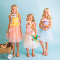 Three children in pastel dress up outfits hold dolls beside a toy pram. Dinkum Dolls imaginative play scene in soft pink blue and yellow tones