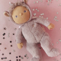Dinky Dinkums Uma Unicorn doll in a lilac purple outfit lying on a pink blanket scattered with silver and black stars