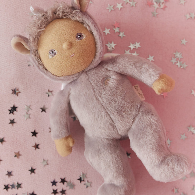 Dinky Dinkums Uma Unicorn doll in a lilac purple outfit lying on a pink blanket scattered with silver and black stars