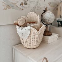 Buttercream rattan nesting basket set styled on a nursery cabinet with a floral cloth and brush inside. Olli Ella Nursery storage for toys and essentials
