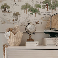 Buttercream rattan basket set by Olli Ella Nursery displayed on a dresser with nursery decor and a whimsical woodland wall mural