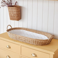 Olli Ella Nursery Bayu rattan changing basket with a soft white quilted liner and sturdy handles displayed on a wooden nursery dresser