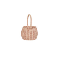 Small rose pink rattan basket with a rounded shape and tall loop handle shown against a white background for children to carry treasures