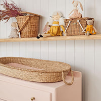 Soft rose organic cotton liner fitted inside a woven changing basket on a blush dresser in a cosy nursery with Olli Ella dolls and accessories from Olli Ella Nursery