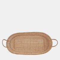 Natural rattan baby changing basket with a rounded woven design and vegan leather handles from Olli Ella Nursery on a light background