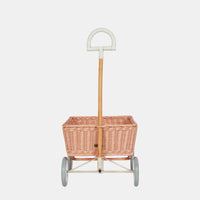 Rose rattan toy wagon with a woven basket and wooden handle on four grey wheels by Olli Ella Kids Rattan for imaginative play and collecting treasures