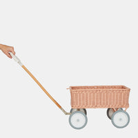 Olli Ella rose rattan Wonder Wagon with four wheels and a long wooden pull handle shown on a light background