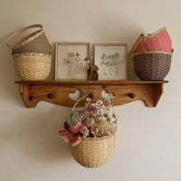 Small bamboo basket filled with dried flowers hangs beneath a wooden shelf with two colourful woven baskets displayed above by Olli Ella Kids Rattan