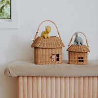 Large and small rattan house baskets with loop handles and woven roofs displayed on a wooden bench with animal toys inside Olli Ella Kids Rattan style play storage