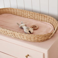 Olli Ella Nursery rose padded liner fitted inside a woven changing basket with a soft toy and wooden ring resting on top in a peaceful nursery setting